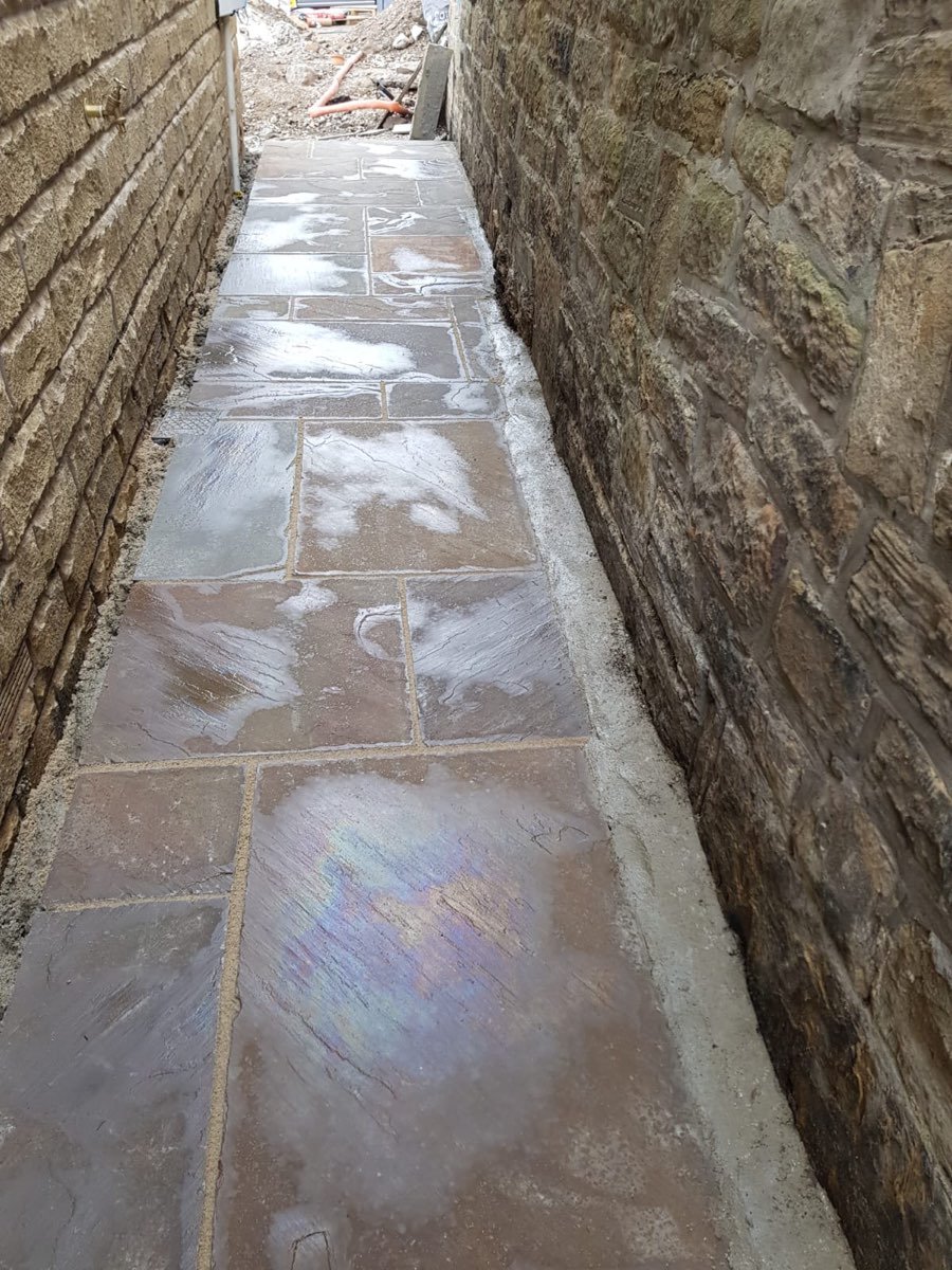 Narrow natural stone flagged pathway between stone walls
