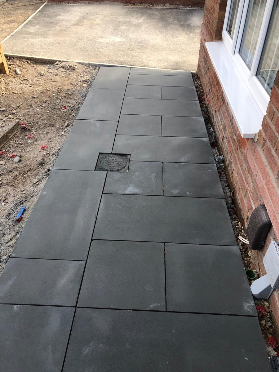 Large-format dark porcelain paving laid beside a house
