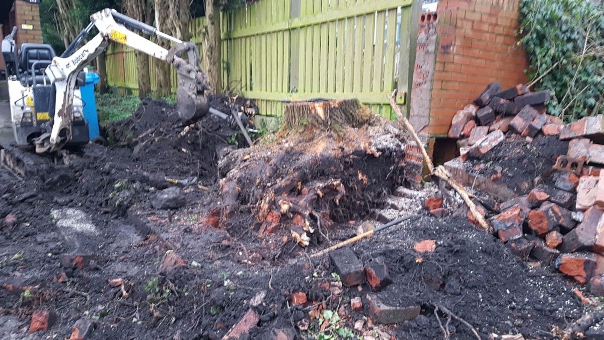 Mini digger clearing demolished brick rubble on site