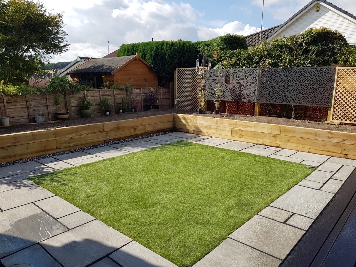 Artificial grass lawn bordered by a porcelain patio and timber sleeper retaining wall